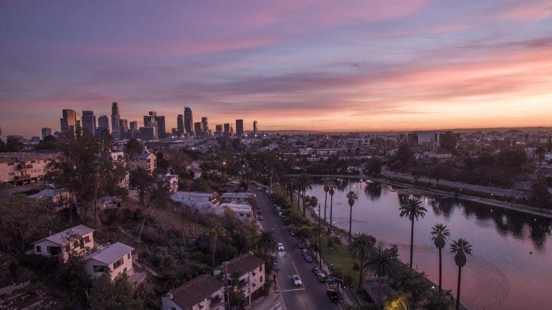Los Angeles at dusk, with palm-lined Echo Park Lake in the foreground and the downtown skyline behind