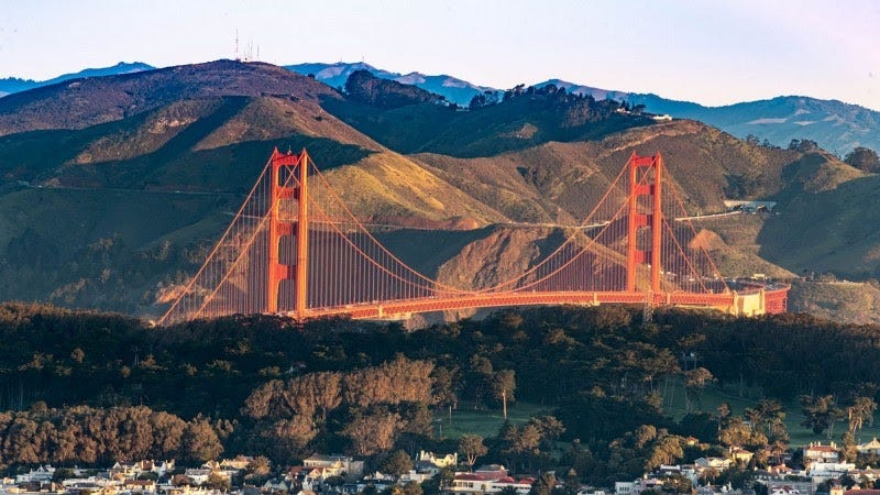 The Golden Gate Bridge in front of the Marin Headlands, San Francisco rooftops in the foreground
